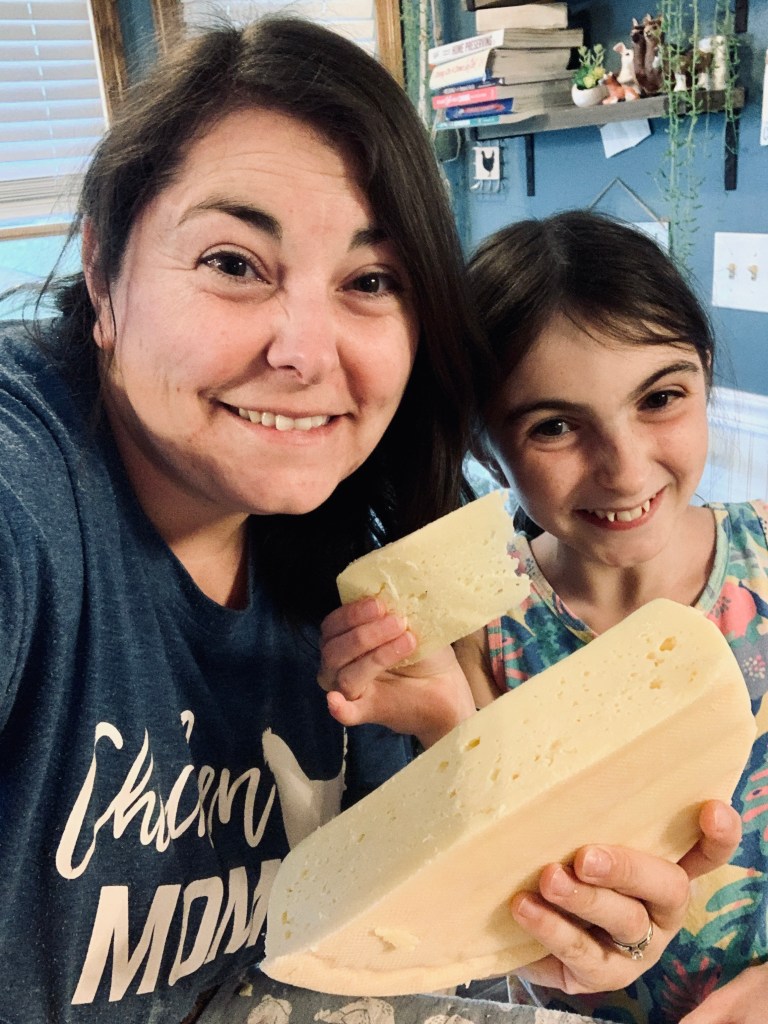 Mother and daughter happily hold up homemade cheese