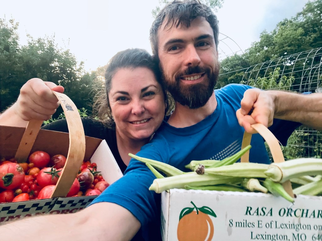 Man and woman hold up produce from their garden